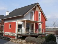 Rodinn&yacute; dům s červenou fas&aacute;dou postaven&yacute; nad vodou.