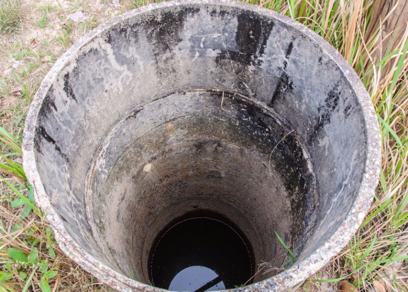 Studna před vyčištěním plná špinavé vody a kalu.