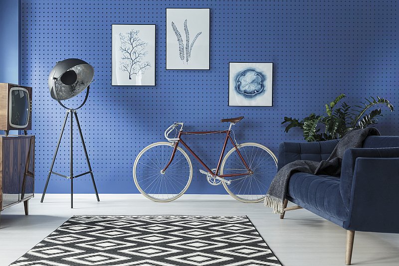 distort-interier-v-modre-barve-sedacka-retro-nabytek-pokojova-lampa-obrazy-jizdni-kolo