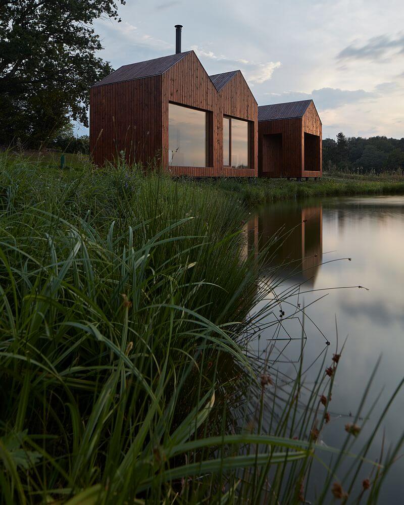 drevena-chata-u-rybnika-vysocina-exterier-velkoformatova-okna-drevena-fasada-hladina-rybnika-traviny-u-brehu