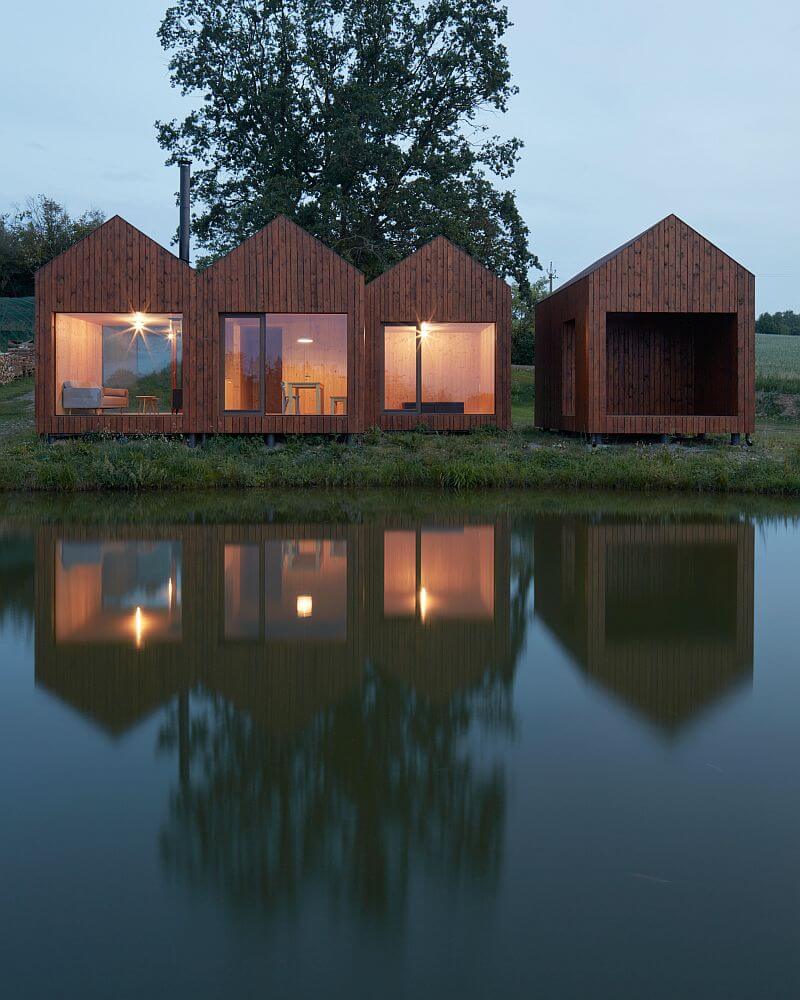 drevena-chata-u-rybnika-vysocina-exterier-velkoformatova-okna-drevena-fasada-hladina-rybnika-vecer