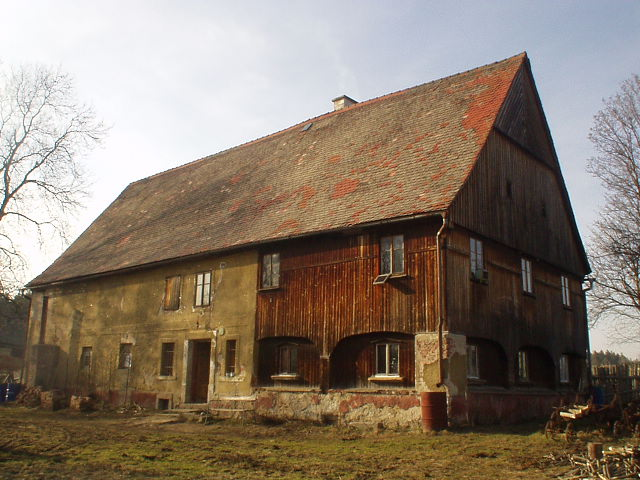 Fotografie neudržovan&eacute;ho podst&aacute;vkov&eacute;ho domu na Fr&yacute;dlantsku s palubkov&yacute;m obkladem.