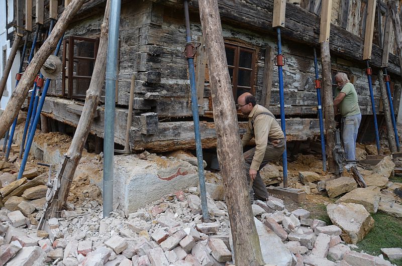 Muži rozeb&iacute;raj&iacute;c&iacute; spodn&iacute; tr&aacute;my rouben&eacute; světnice podst&aacute;vkov&eacute;ho domu.
