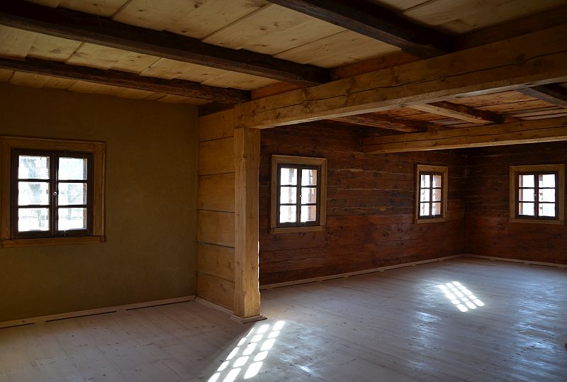 Interi&eacute;r světnice podst&aacute;vkov&eacute;ho domu s rouben&yacute;mi stěnami a tr&aacute;mov&yacute;m stropem.