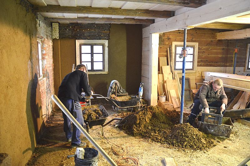 Aplikace hliněn&eacute; směsi ve světnici podst&aacute;vkov&eacute;ho domu.