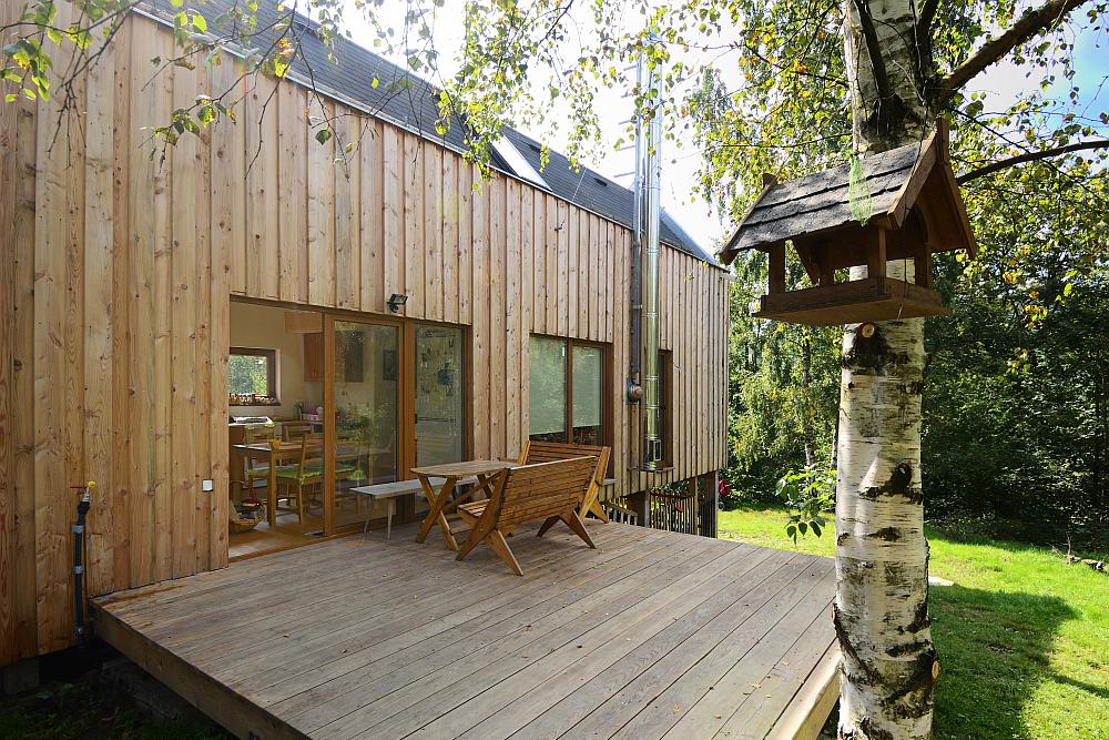 Dům ve svahu obložen&yacute; dřevem s terasou.