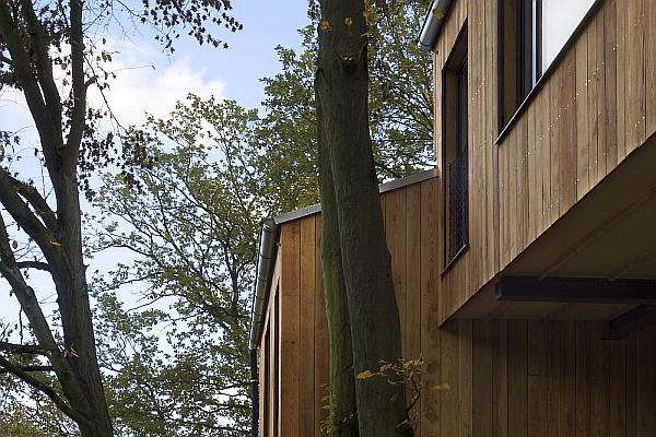 Dvojdům ve svahu na pilotech v Zadn&iacute; Třebani mezi stromy.