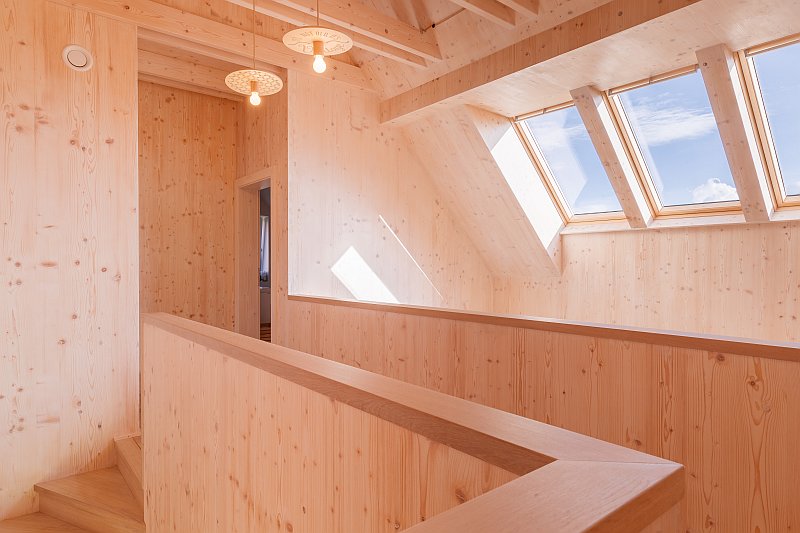 navsteva-drevostavby-dotazeny-v-kazdem-detailu-prodesi-domesi-interier-galerie-chodba-osvetleni-masivni-drevene-panely-novatop