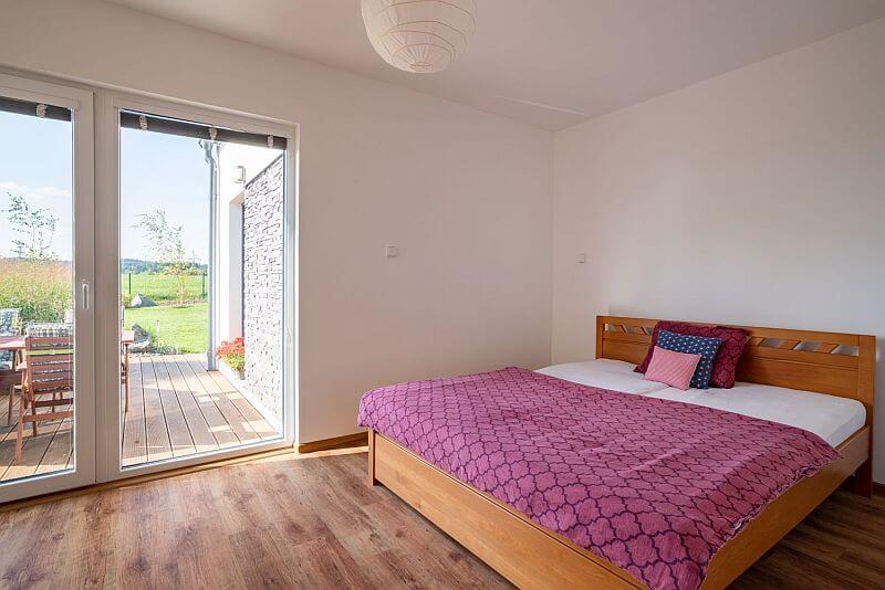 navsteva-drevostavby-ve-vlastnich-stopach-ms-haus-interier-loznice-drevena-postel-vstup-na-terasu